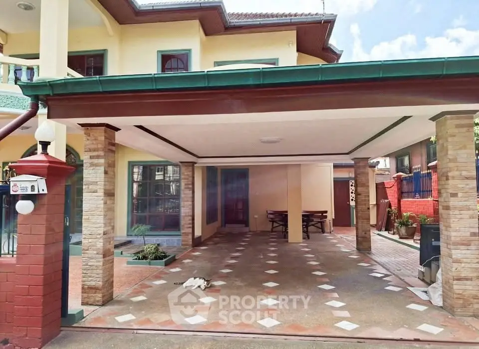 Spacious covered parking area in a charming suburban home with brick accents and lush surroundings.