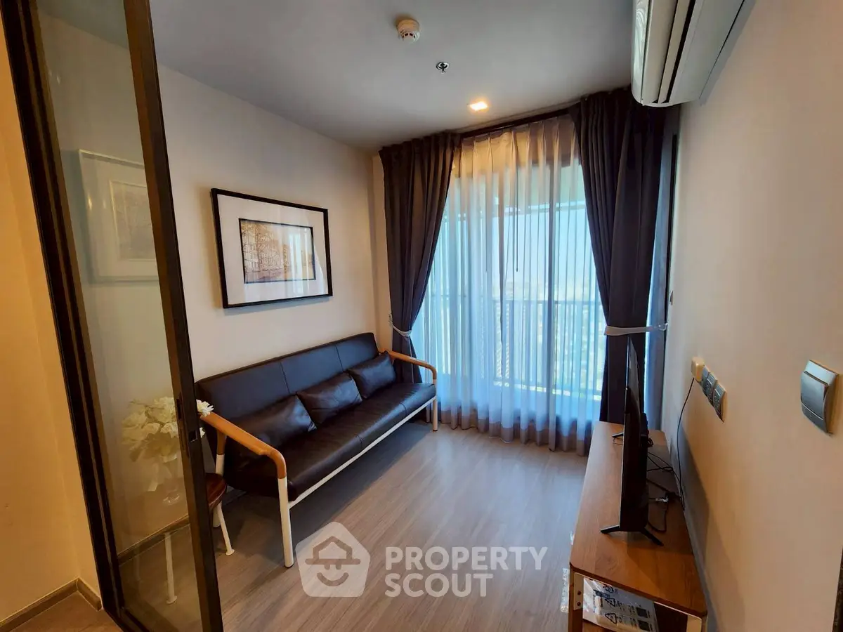 Modern living room with sleek furniture and large window offering natural light.