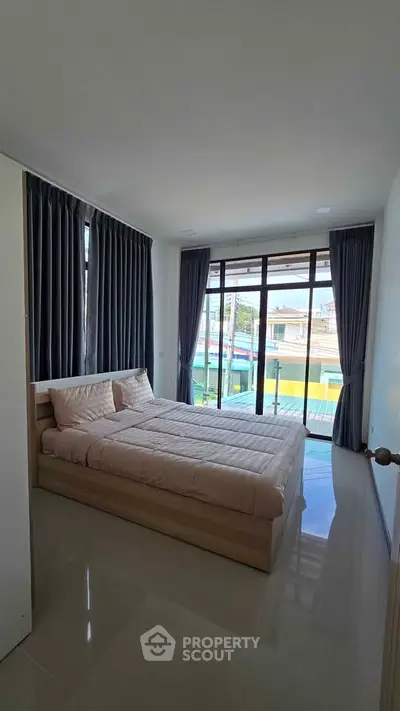 Spacious bedroom with large windows and modern decor in a bright apartment.
