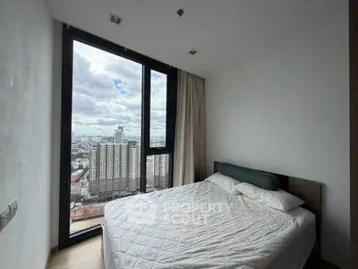 Modern bedroom with large window offering stunning city view in high-rise apartment.