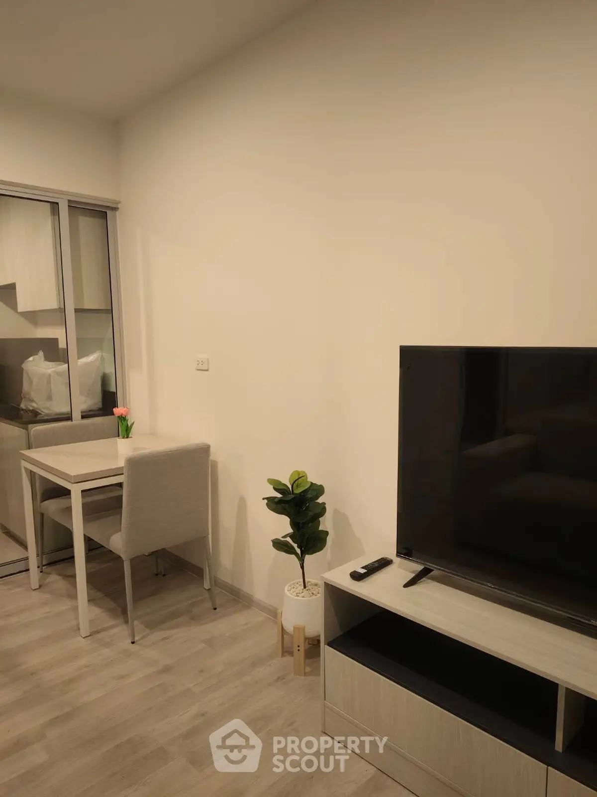 Modern living room with sleek TV setup and cozy dining area in stylish apartment.