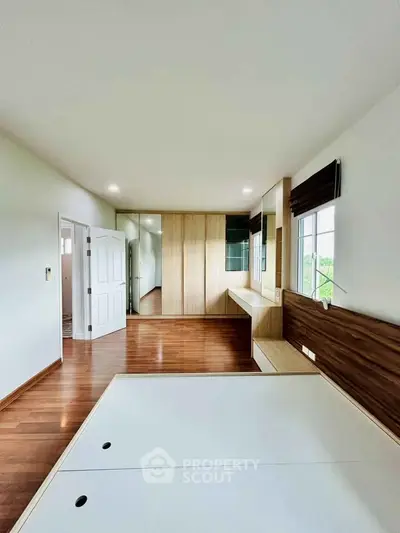 Spacious bedroom with wooden flooring and built-in wardrobe