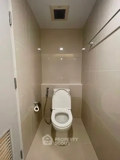 Modern bathroom with sleek toilet and beige tiles, ideal for compact spaces.