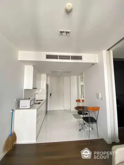 Modern kitchen with sleek white cabinetry and compact dining area in a stylish apartment.