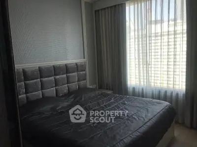 Cozy bedroom with plush headboard and large window with sheer curtains.