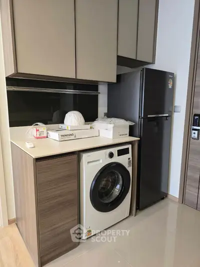 Modern kitchen with sleek cabinets, washing machine, and fridge in a compact layout.