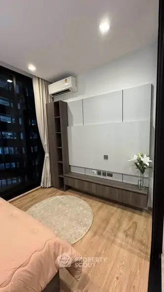 Modern bedroom with wooden flooring, built-in shelving, and air conditioning unit.