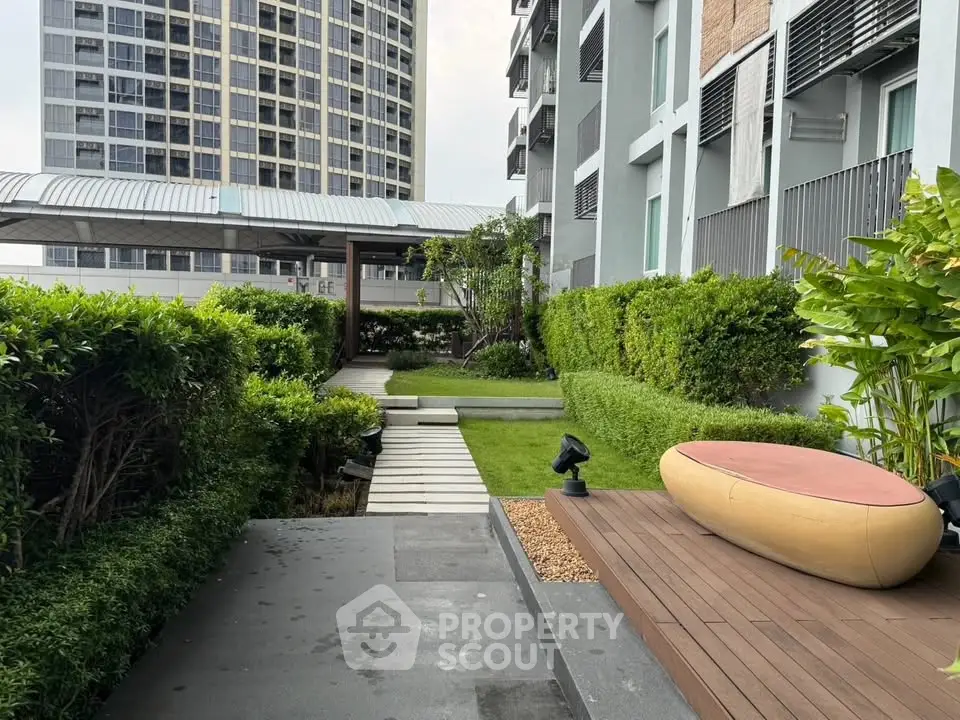 Modern apartment building with lush garden and outdoor seating area, perfect for relaxation.