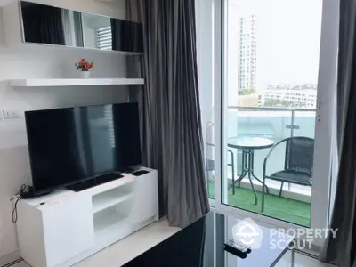 Modern living room with balcony access and city view, featuring sleek furniture and large TV.