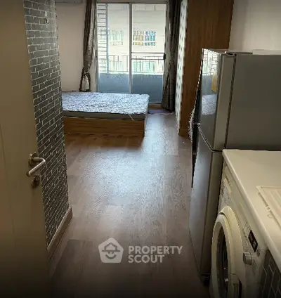Modern studio apartment with balcony, featuring a washing machine and refrigerator.