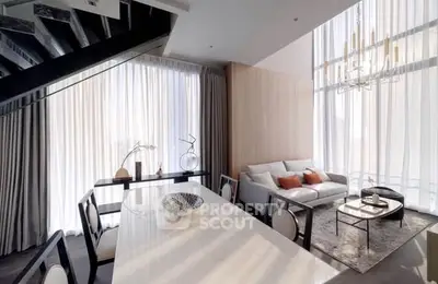 Luxurious modern living room with high ceilings, elegant chandelier, and stylish decor.