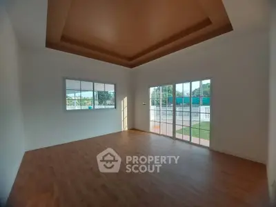 Spacious empty room with wooden flooring and large windows