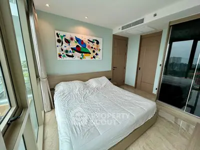 Modern bedroom with large windows and abstract art, offering a serene and stylish living space.