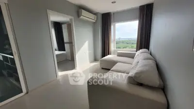 Spacious living room with large window and modern sofa, offering serene views.