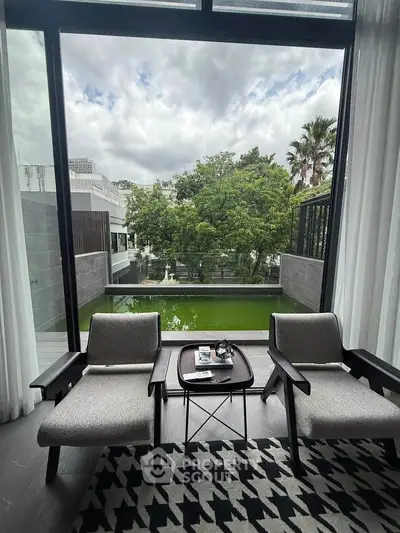 Luxurious living room with large window overlooking serene garden and pool view