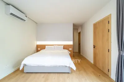 Modern bedroom with minimalist design and wooden flooring, featuring a cozy bed and air conditioning.