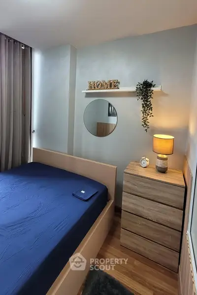 Cozy bedroom with modern decor, featuring a stylish bed, wooden dresser, and elegant lighting.