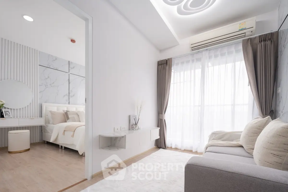 Modern living room with elegant decor and natural light, adjacent to a stylish bedroom.