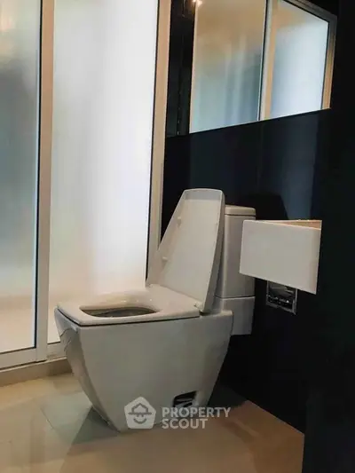 Modern bathroom with sleek toilet and frosted glass partition