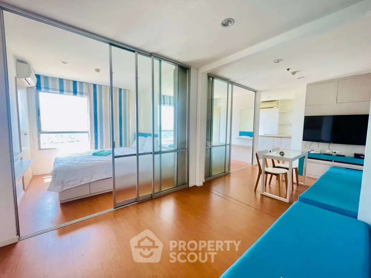 Modern apartment with open layout, featuring a cozy living area and bedroom separated by glass doors.