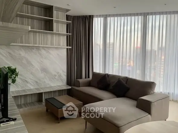 Modern living room with stylish furniture and floor-to-ceiling windows offering city views.