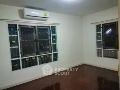Spacious room with air conditioning and large windows in a well-lit apartment.