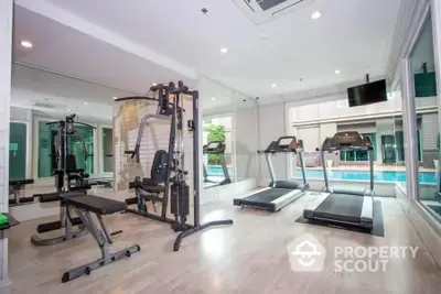 Modern gym with state-of-the-art equipment and pool view in luxury real estate property.