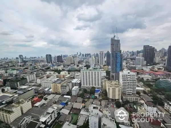 Expansive cityscape view from a high-rise, showcasing a blend of residential and commercial buildings under a dramatic sky.