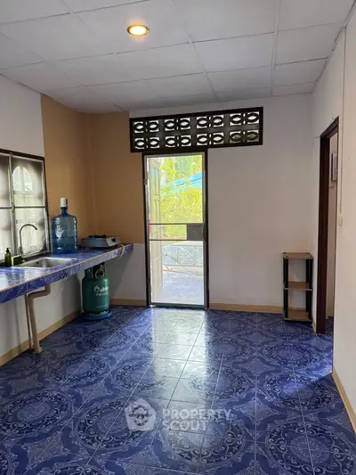 Spacious kitchen with blue patterned floor and ample natural light, featuring a gas stove and open layout.