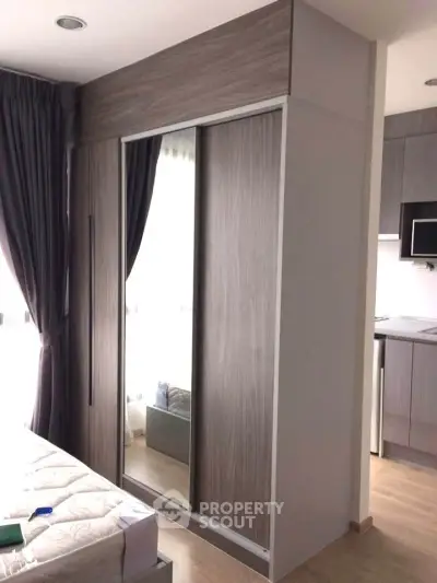 Modern bedroom with built-in wardrobe and partial kitchen view