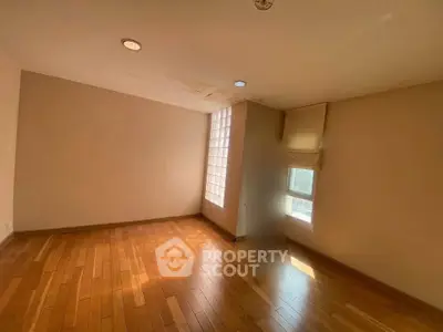 Spacious empty room with wooden flooring and natural light, ideal for customization.