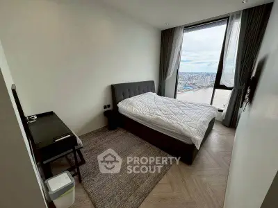 Modern bedroom with city view, featuring a cozy bed and sleek desk setup.