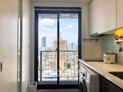Modern kitchen with city view from balcony, featuring sleek cabinets and washing machine.