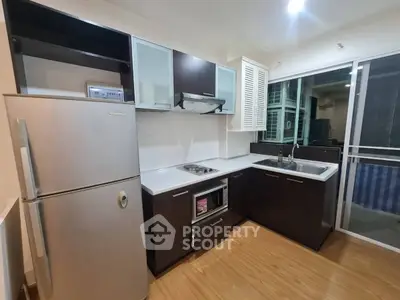 Modern kitchen with sleek cabinets, stainless steel fridge, and electric stove in a stylish apartment.
