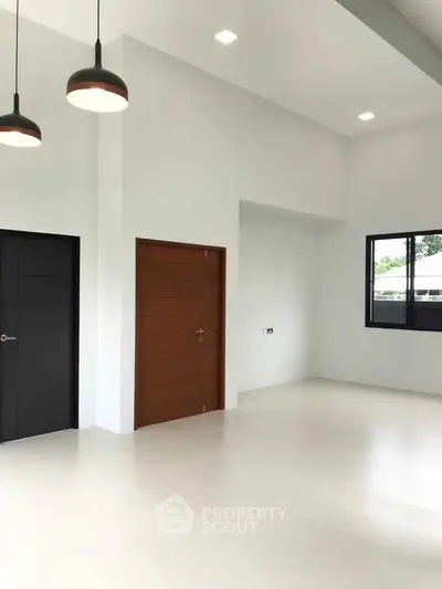 Spacious modern interior with high ceilings and minimalist design, featuring sleek doors and large windows.