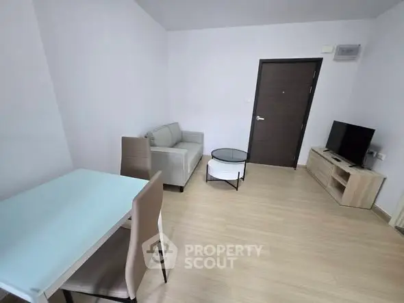 Modern living room with minimalist furniture and sleek design, featuring a cozy sofa and entertainment unit.