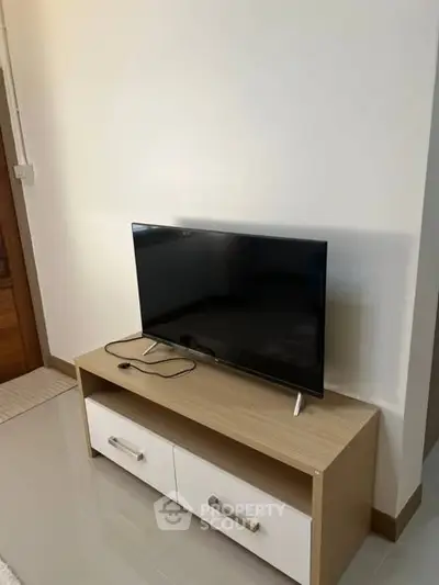Modern living room with sleek TV on stylish wooden stand, perfect for cozy entertainment nights.