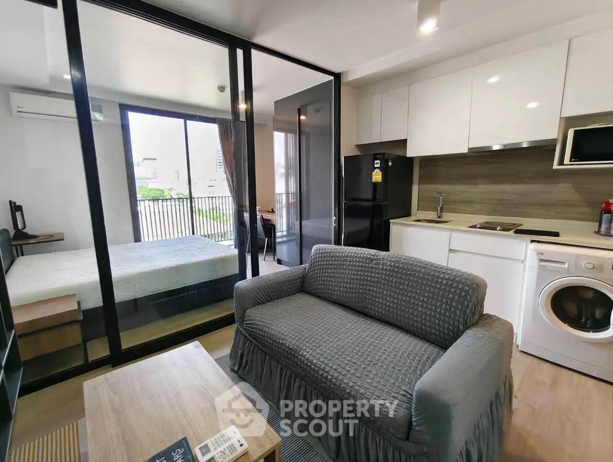 Modern studio apartment with open layout, featuring a cozy living area, compact kitchen, and bedroom with balcony view.