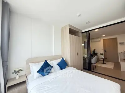 Modern bedroom with cozy decor and sliding glass doors leading to living area.