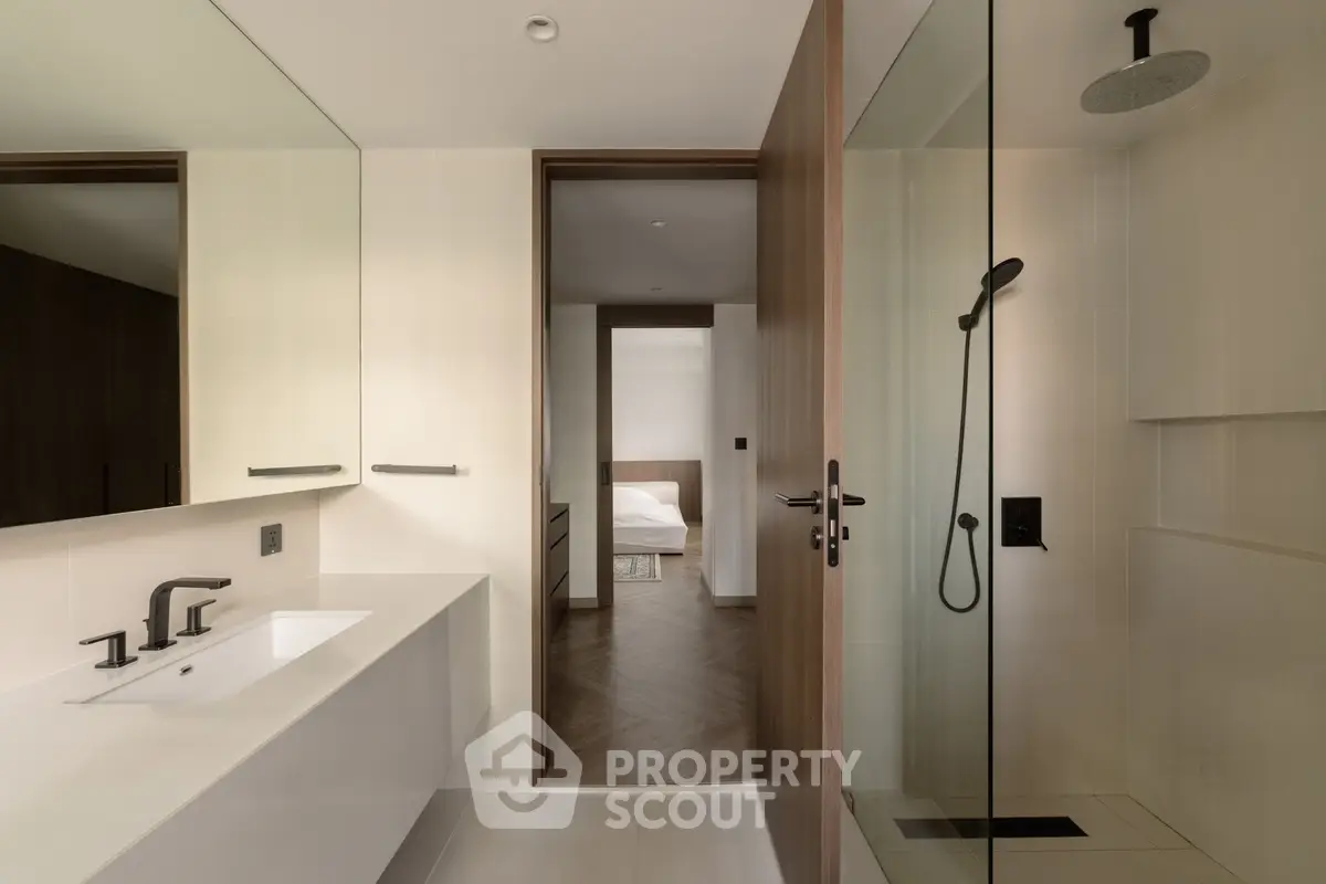 Modern bathroom with sleek fixtures and a view into a stylish bedroom