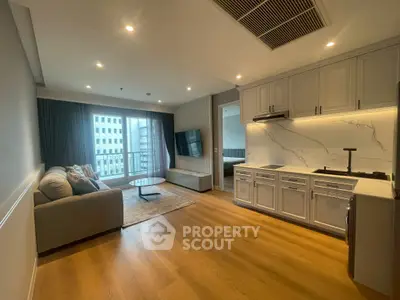 Modern open-layout living room with kitchen, featuring sleek cabinetry and large window with city view.