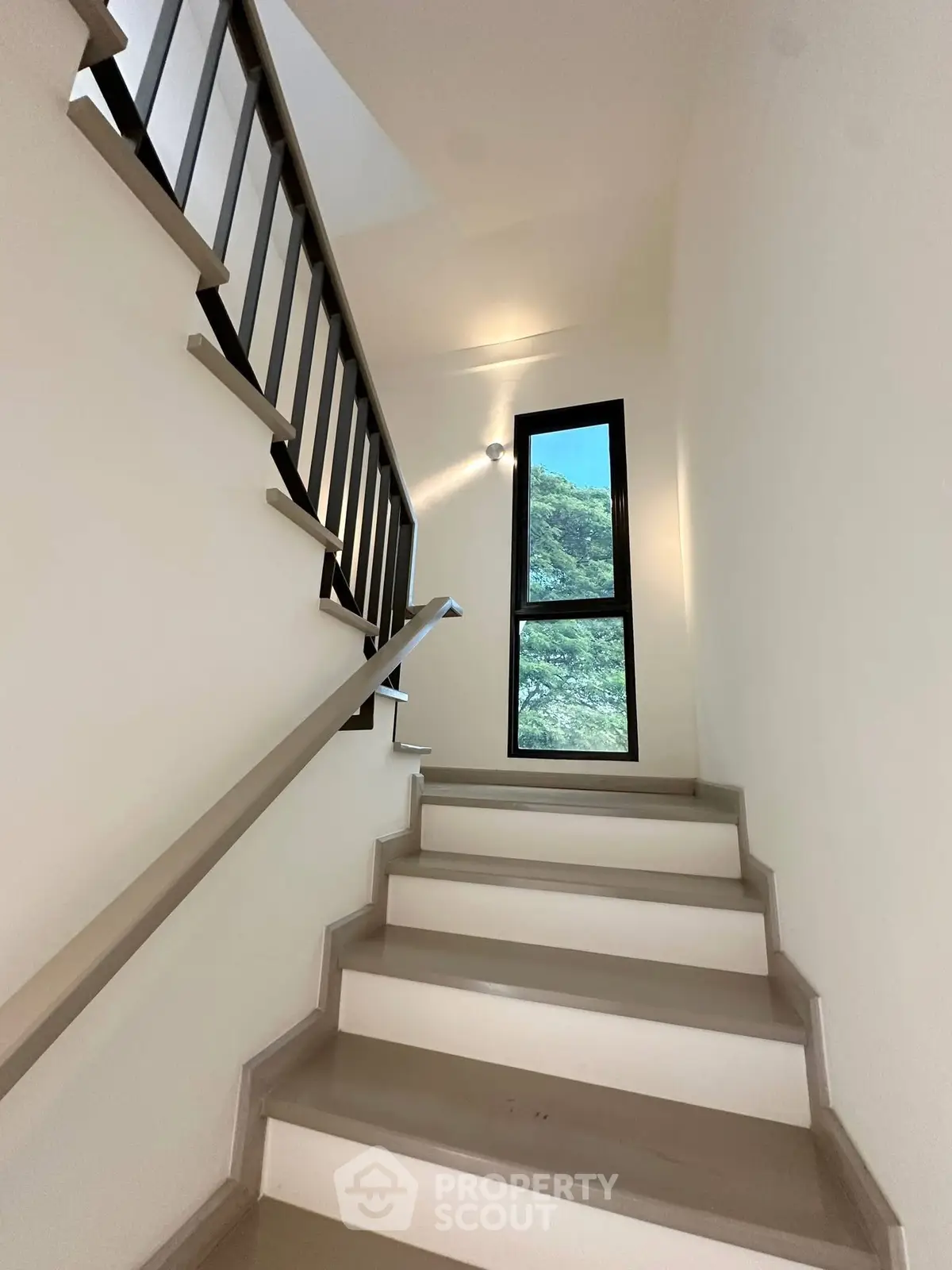 Modern staircase with sleek railing and large window offering scenic views.