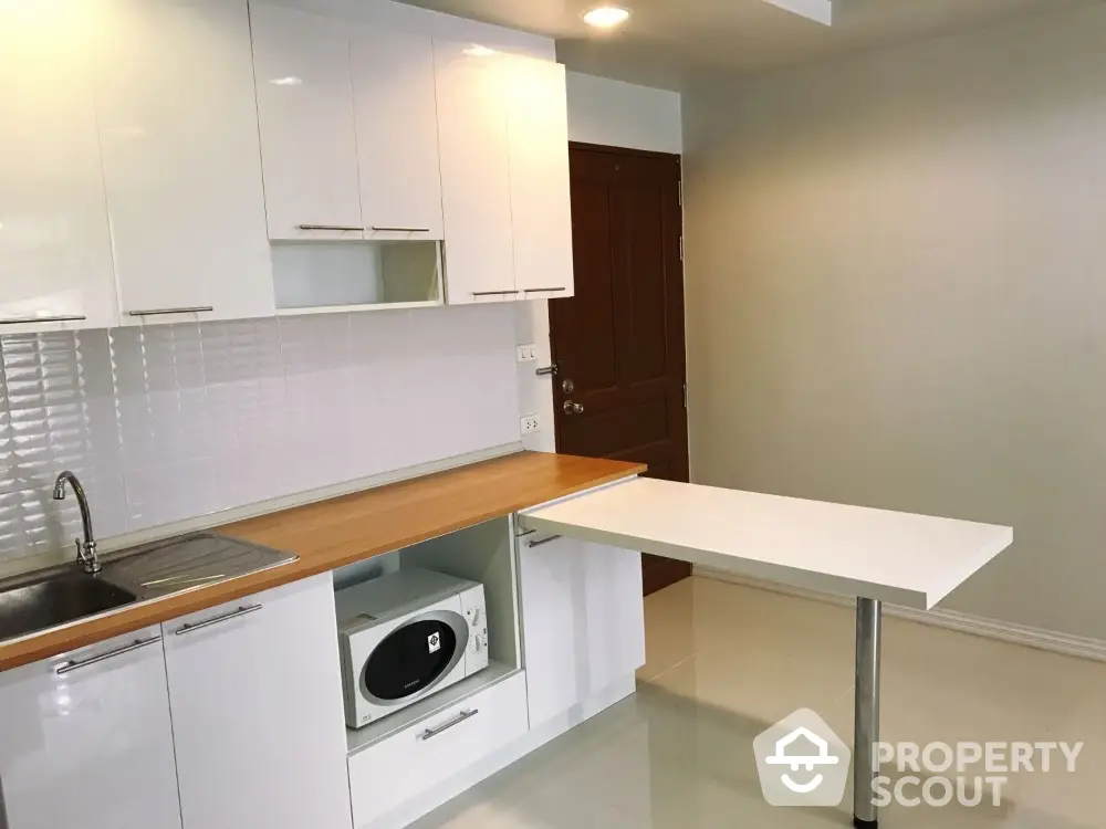 Modern kitchen with sleek white cabinets and built-in microwave