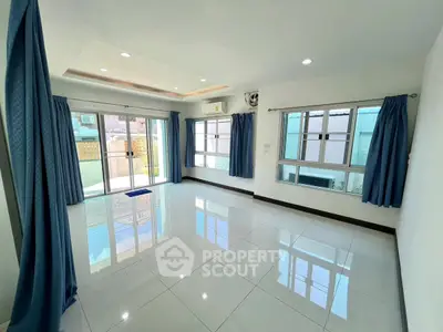 Spacious living room with large windows and blue curtains, offering abundant natural light.