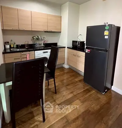 Modern kitchen with wooden cabinets, dining table, and appliances in cozy apartment.