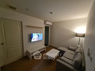 Cozy living room with modern sofa, wall-mounted TV, and stylish lighting.