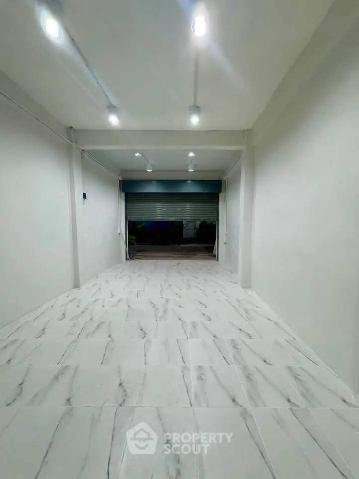 Spacious garage with modern lighting and sleek tiled flooring, perfect for secure parking or storage.