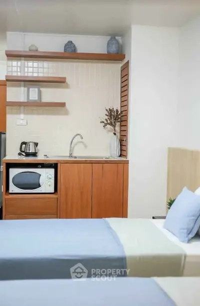 Cozy bedroom with kitchenette featuring microwave and kettle, ideal for compact living.