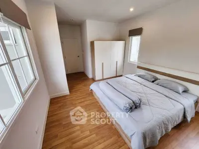 Spacious bedroom with wooden flooring and large windows for natural light