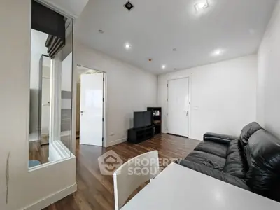 Modern living room with sleek black leather sofa and wooden flooring, perfect for cozy gatherings.